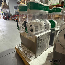 Load image into Gallery viewer, A commercial slushie maker machine with two green and white dispensers, clear plastic containers, and a silver metal base, photographed in a warehouse setting.